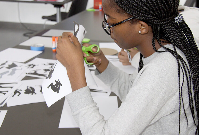 Middle School Harlem Renaissance art project student cutting figures from paper