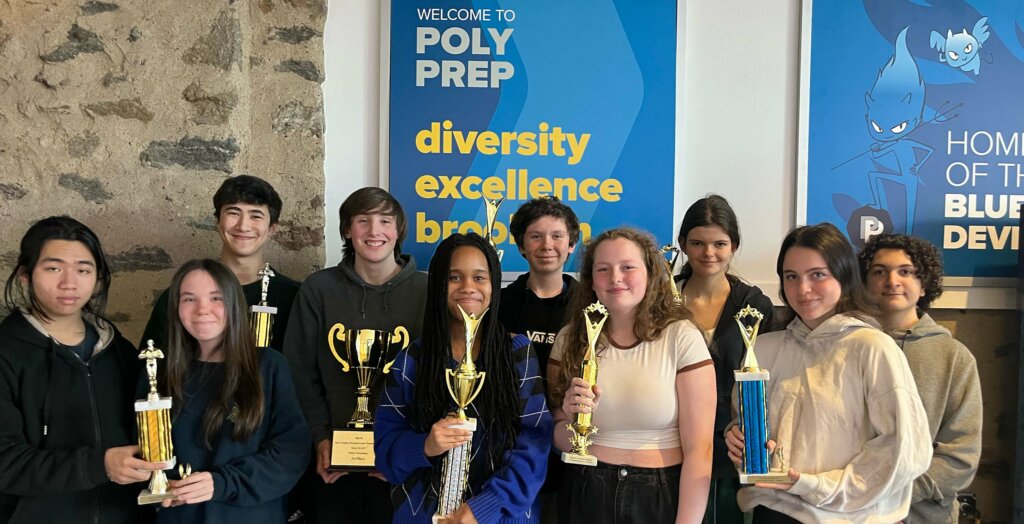 Speech & Debate Team in front of Blue Devil posters