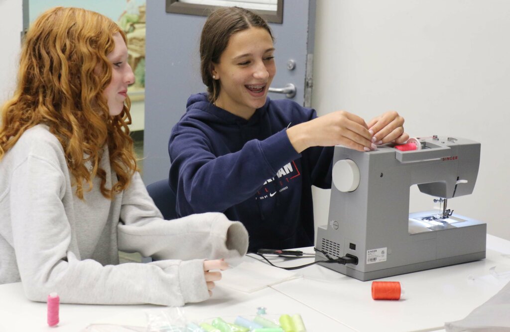 Girls with sewing machine laughing