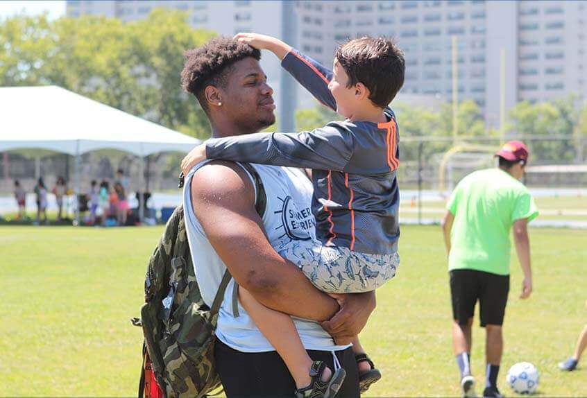 Smiling counselor holding kid at Poly Summer day camp