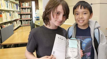 Students holding up Kyle Lukoff's book Too Bright to See